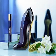 High-heeled shoe with a bottle of perfume and flowers on a reflective surface