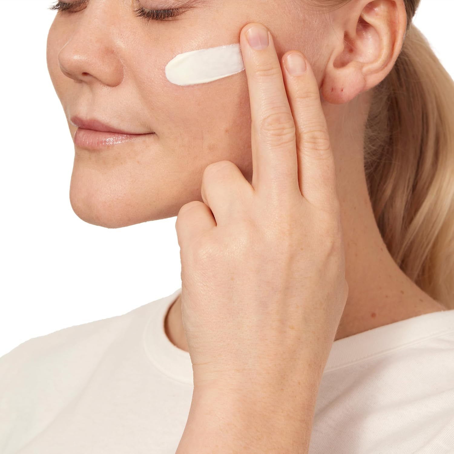 Woman applying cream to her face with a white background